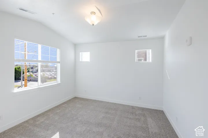 Vaulted ceilings, neutral carpeting, large windows, two additional transom-style windows, and a central semi-flush mount light fixture