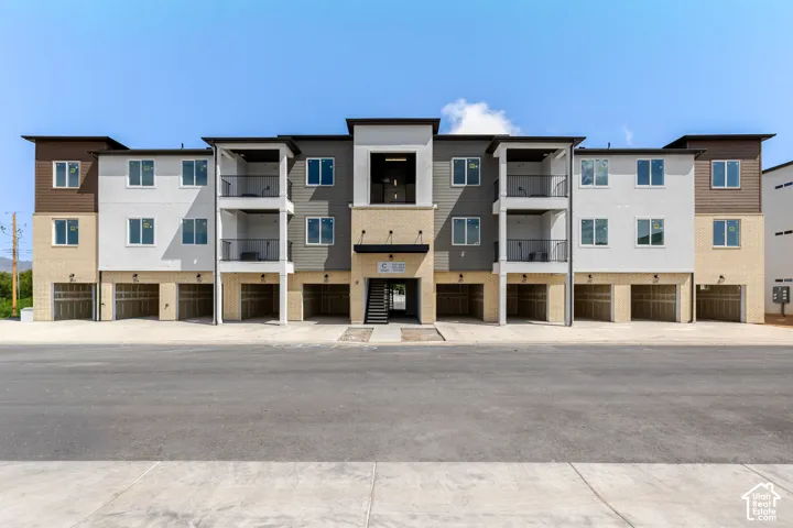 Contemporary multi-story exterior with varying siding materials, individual garages, and multiple balconies with dark railings