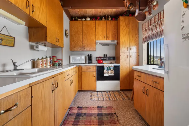 Kitchen featuring white appliances, light countertops, and wood finish cabinetry