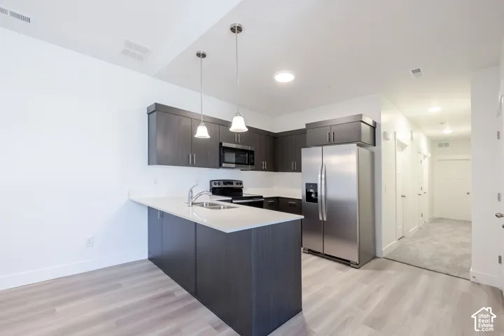Kitchen featuring dark-finish cabinetry, quartz countertops, stainless steel appliances, a peninsula breakfast bar, and pendant lighting