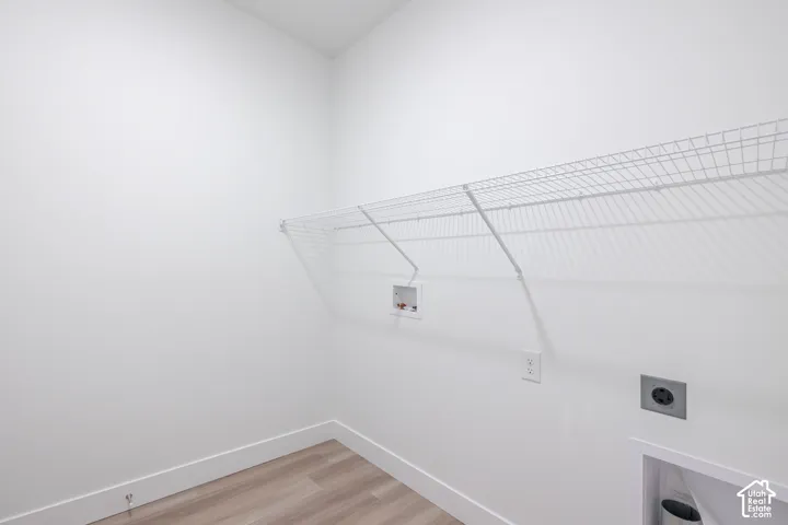 Utility space featuring wood-finish flooring, white walls, and a wall-mounted wire shelving unit