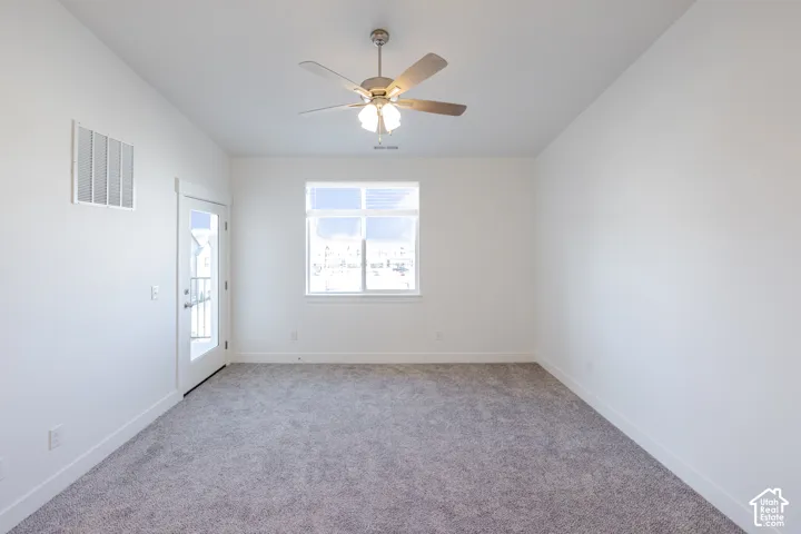 Neutral-toned carpet, ceiling fan with integrated lighting, window with a horizontal pane, and glass-paneled exterior door