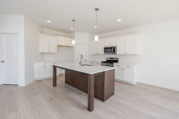 Kitchen featuring light wood-finish flooring, white cabinetry, a central island with a sink, stainless steel appliances, and recessed lighting