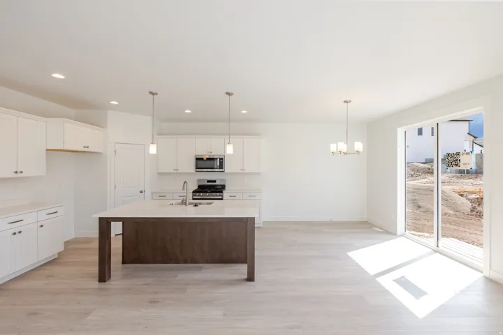 Open-concept kitchen and dining area featuring white cabinetry, a center island with a wood-finish base, stainless steel appliances, and wood-finish flooring