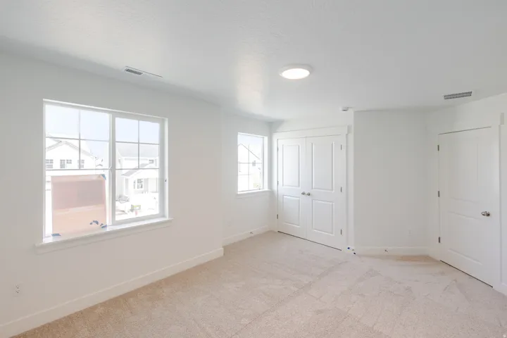 Neutral wall color, light-toned carpet, recessed lighting, white trim throughout, and multiple windows