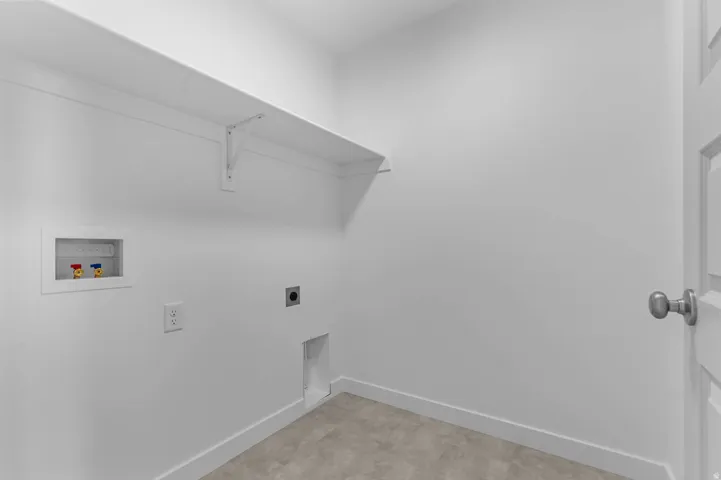 Dedicated laundry area featuring a white support shelf, utility hookups, and a panel door with a silver knob