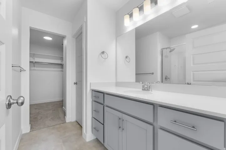 Bathroom vanity featuring a light gray cabinet base, polished chrome hardware, and a white countertop