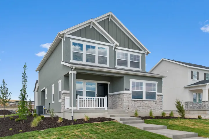 Two-story residence featuring light gray stucco and stone veneer siding