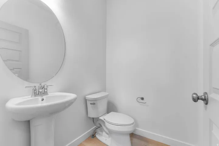 Pedestal sink with chrome faucet and circular mirror