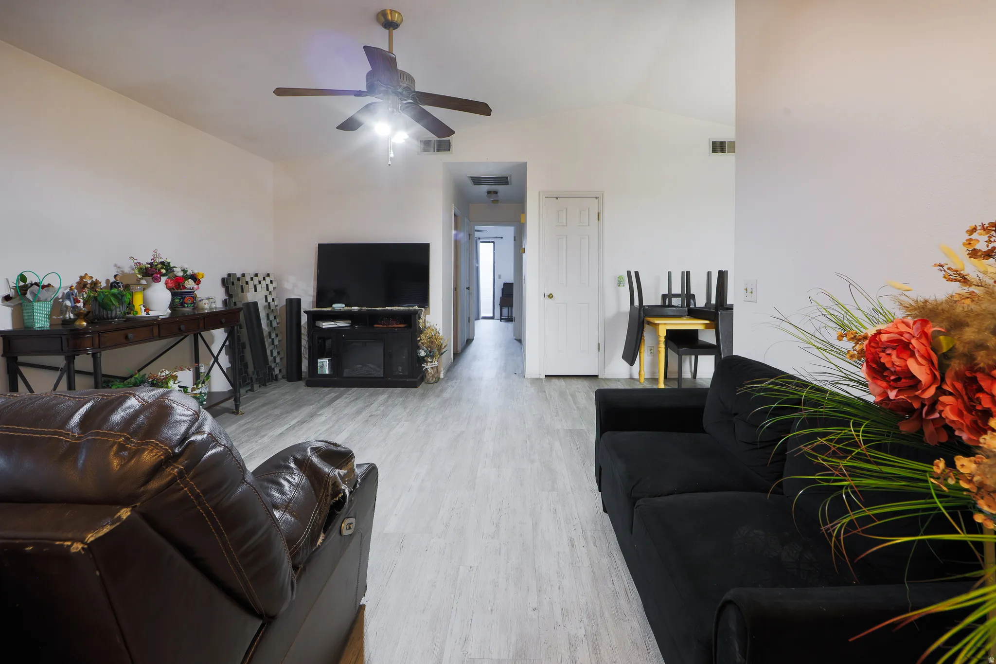 Living room with ceiling fan, vaulted ceiling, and wood finished floors
