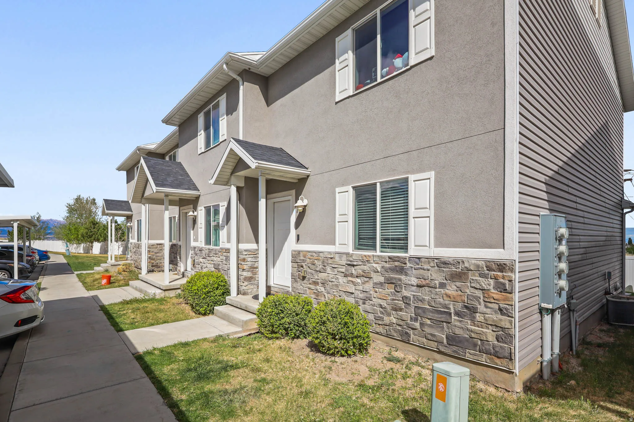 View of front of home featuring stucco siding, stone siding, and a front lawn