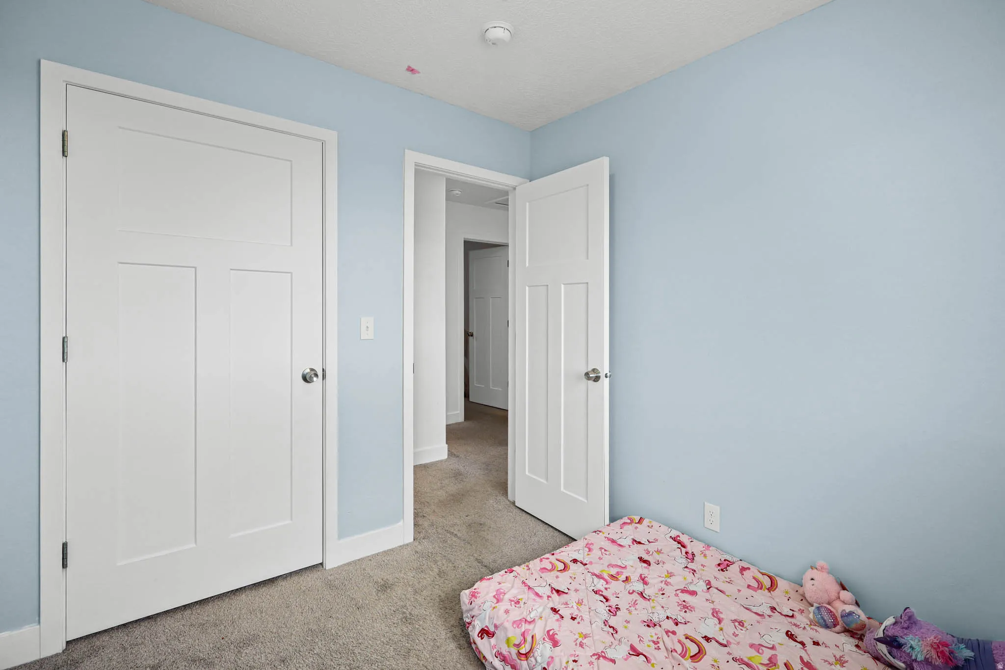 Bedroom featuring light carpet and a textured ceiling