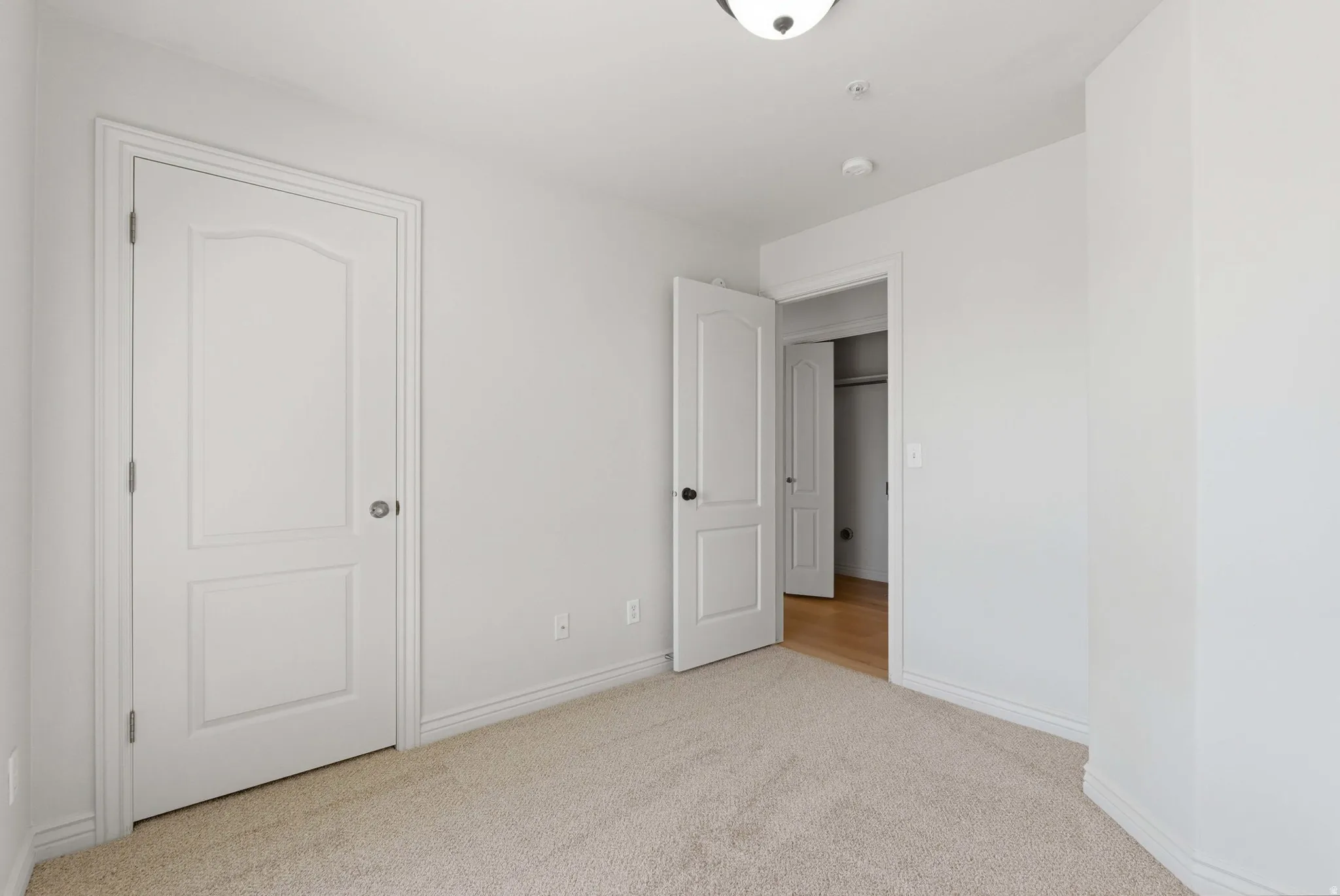 Unfurnished bedroom with light carpet and baseboards