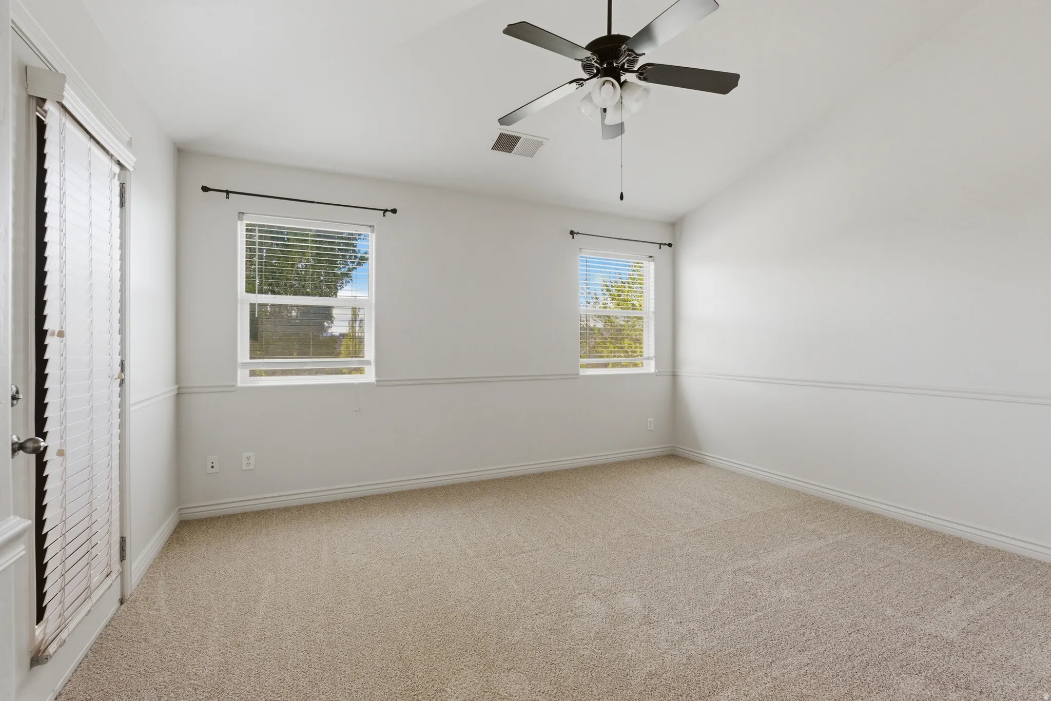 Unfurnished bedroom featuring light carpet, lofted ceiling, and a ceiling fan