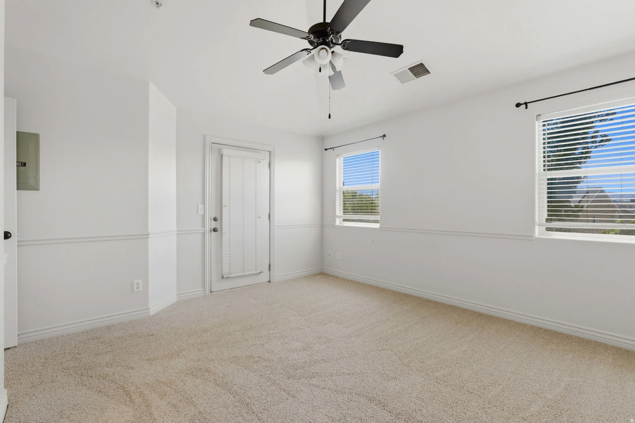 Carpeted spare room featuring electric panel and a ceiling fan
