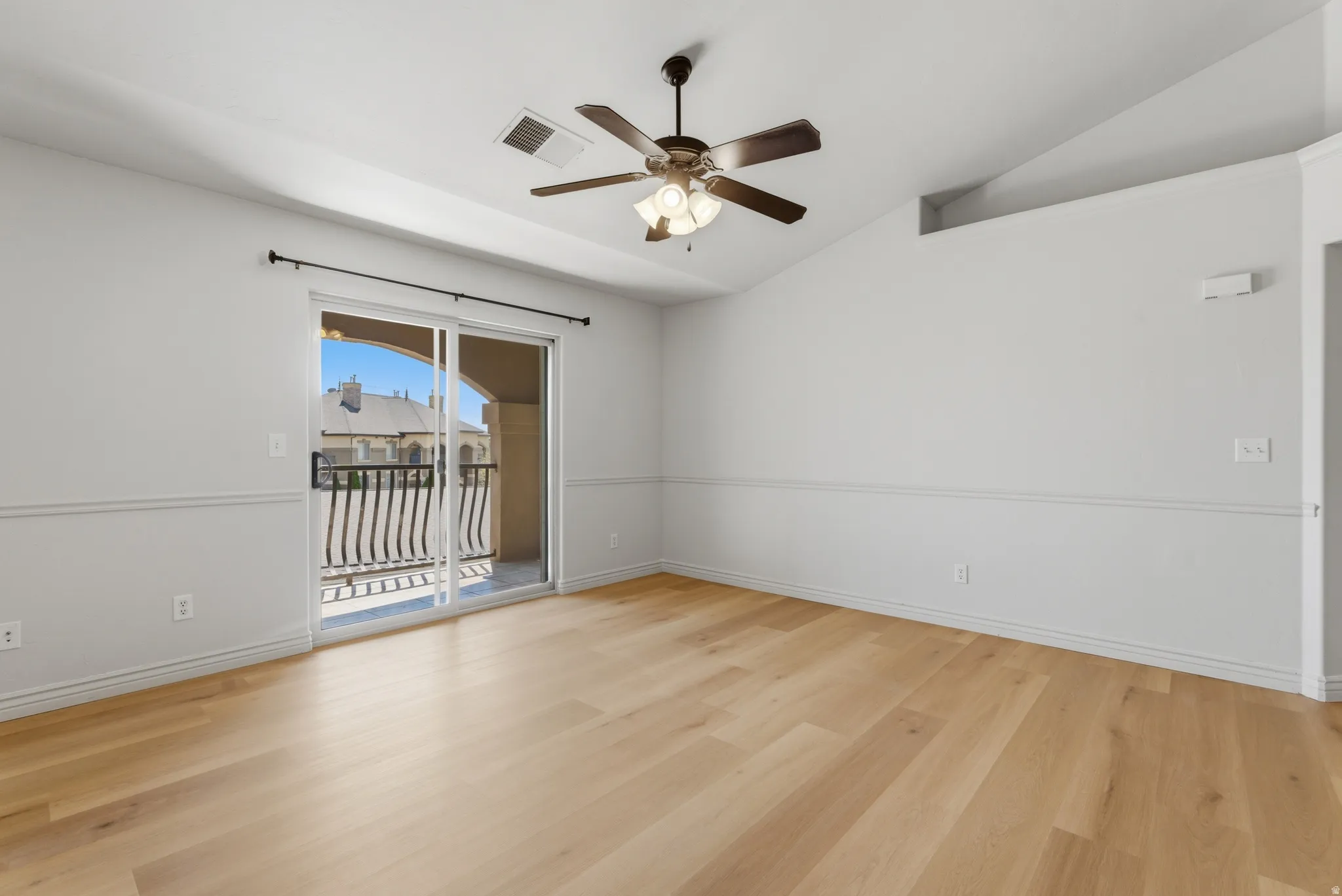 Unfurnished room featuring light wood finished floors, ceiling fan, and vaulted ceiling