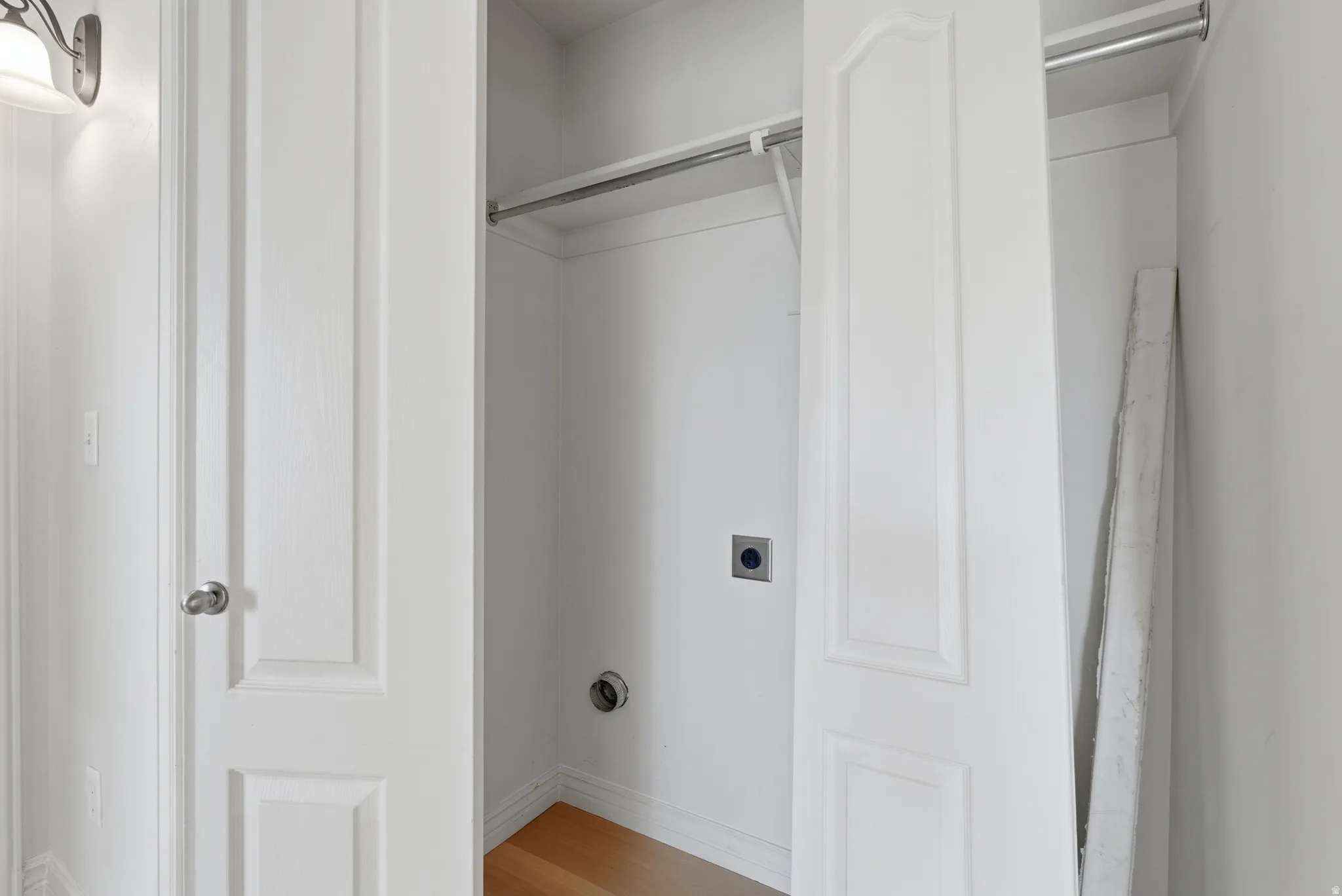 Laundry area with electric dryer hookup and light wood-style flooring