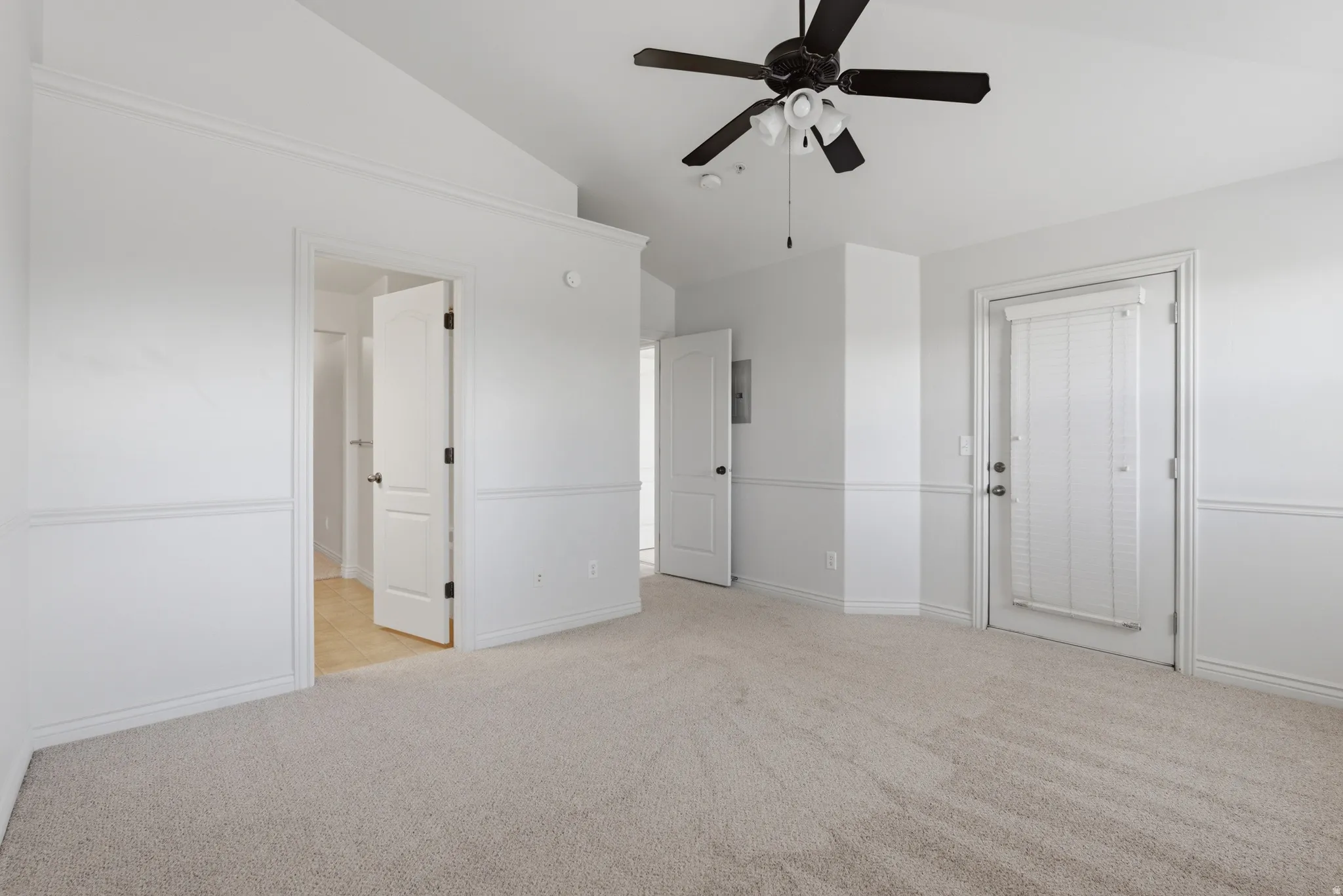 Unfurnished bedroom with light colored carpet, lofted ceiling, and ceiling fan