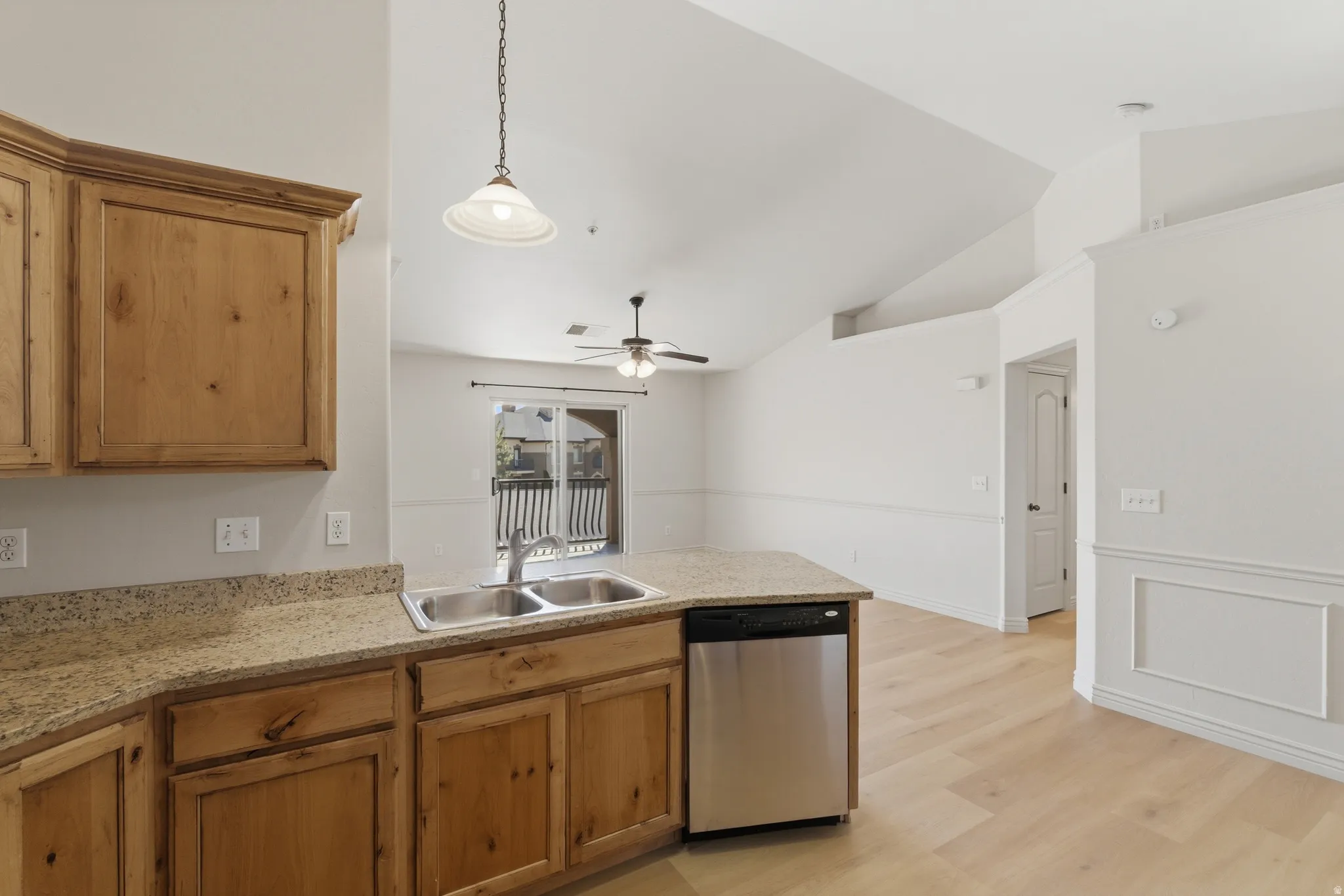 Kitchen featuring a peninsula, stainless steel dishwasher, light wood-style flooring, vaulted ceiling, and ceiling fan