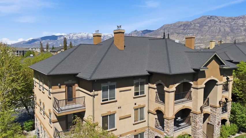 Back of property featuring a chimney, a mountain view, and a balcony