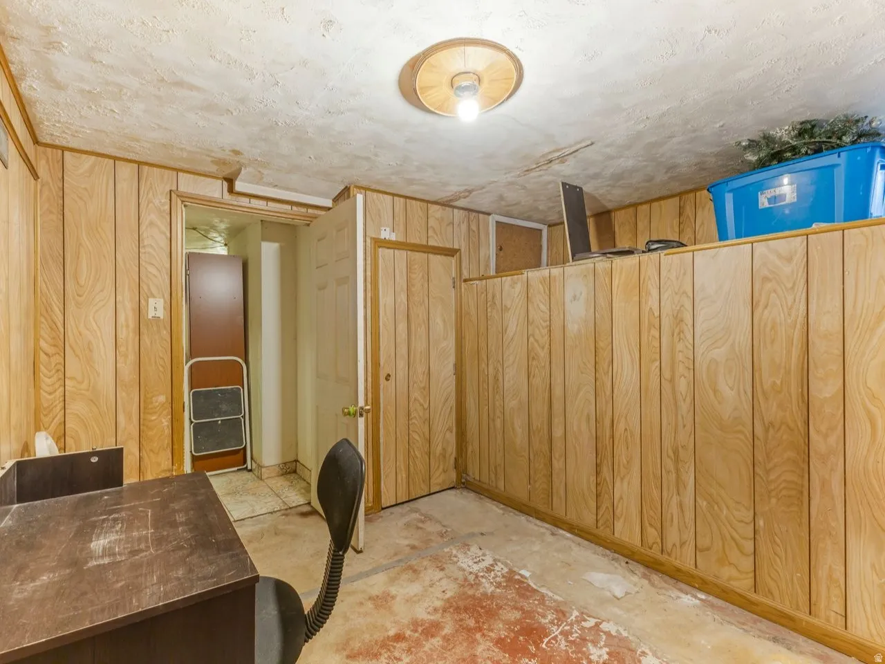 Unfurnished office featuring wooden walls and unfinished concrete floors