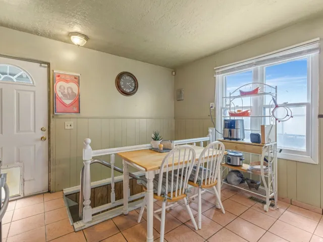 Dining area with a wainscoted wall, plenty of natural light, a textured ceiling, and light tile patterned flooring