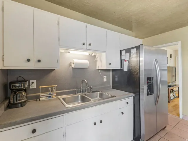 Kitchen featuring stainless steel fridge with ice dispenser, white cabinets, and light tile patterned flooring