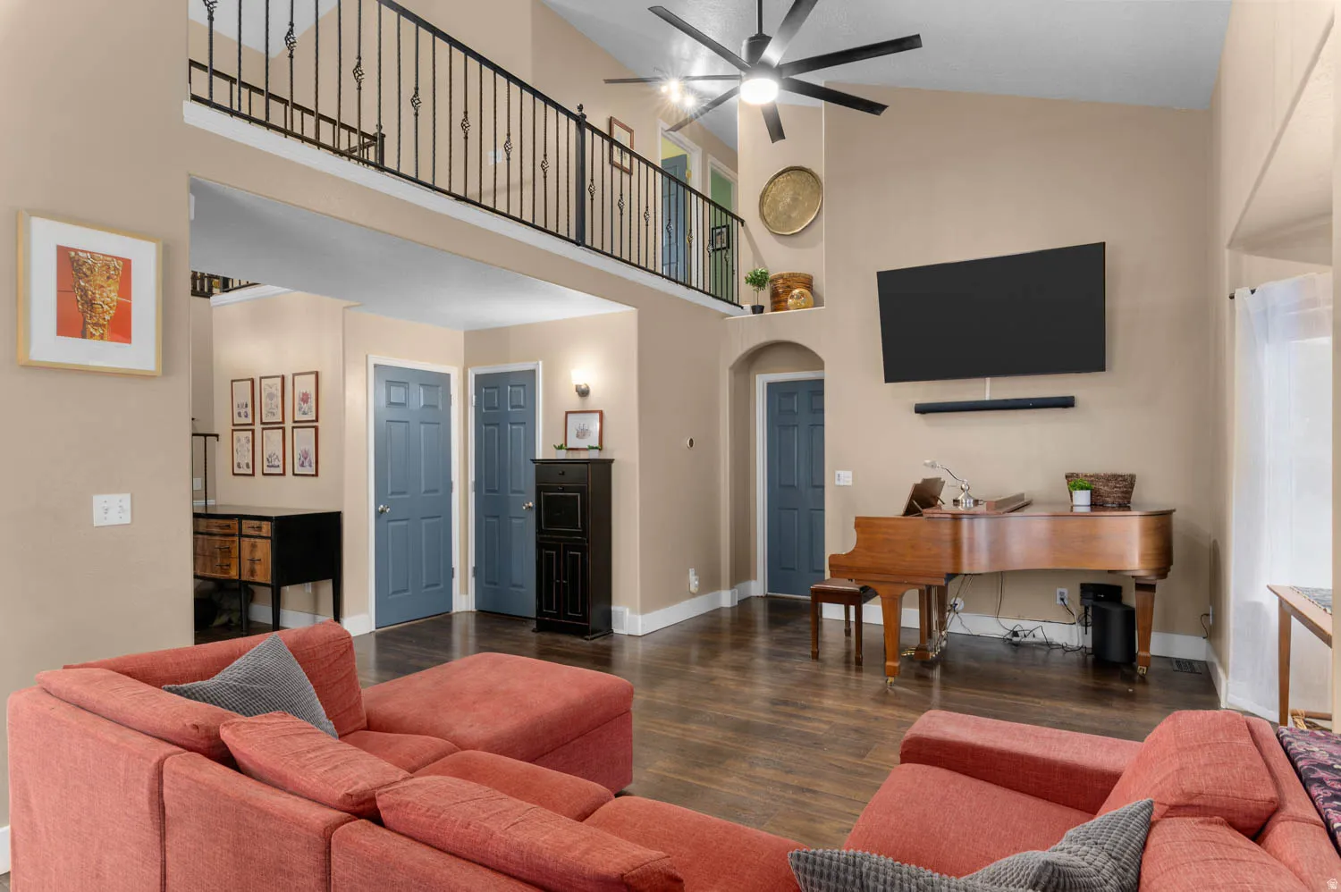 Living area with arched walkways, dark wood-style floors, ceiling fan, and vaulted ceiling