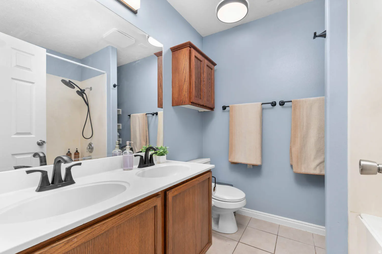 Full bathroom with double vanity and light tile patterned floors