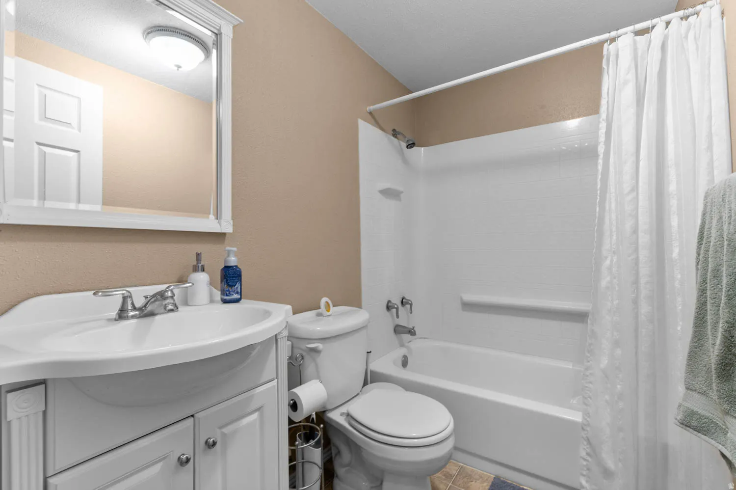 Full bath featuring vanity, shower / bath combo, and a textured wall