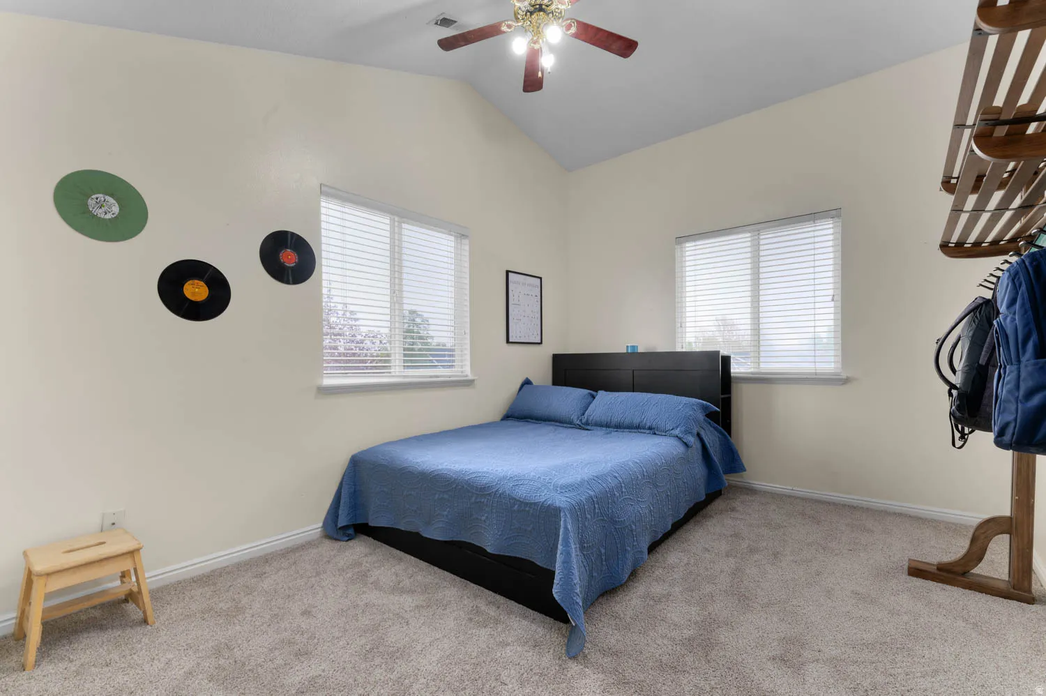 Carpeted bedroom featuring ceiling fan and vaulted ceiling