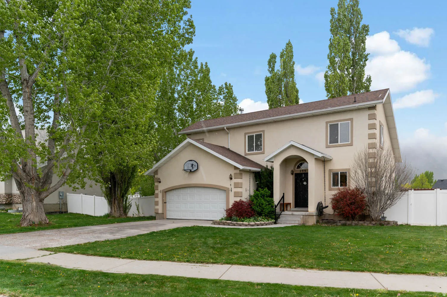 Traditional-style house featuring driveway, an attached garage, and stucco siding