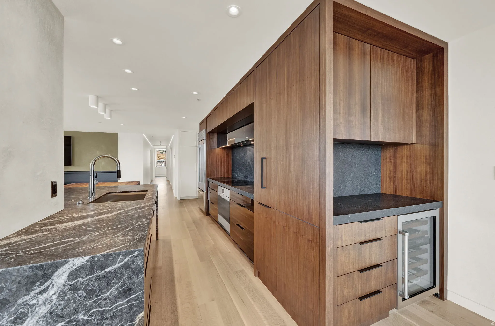Kitchen featuring modern cabinets, recessed lighting, light wood-type flooring, dark stone counters, and wine cooler