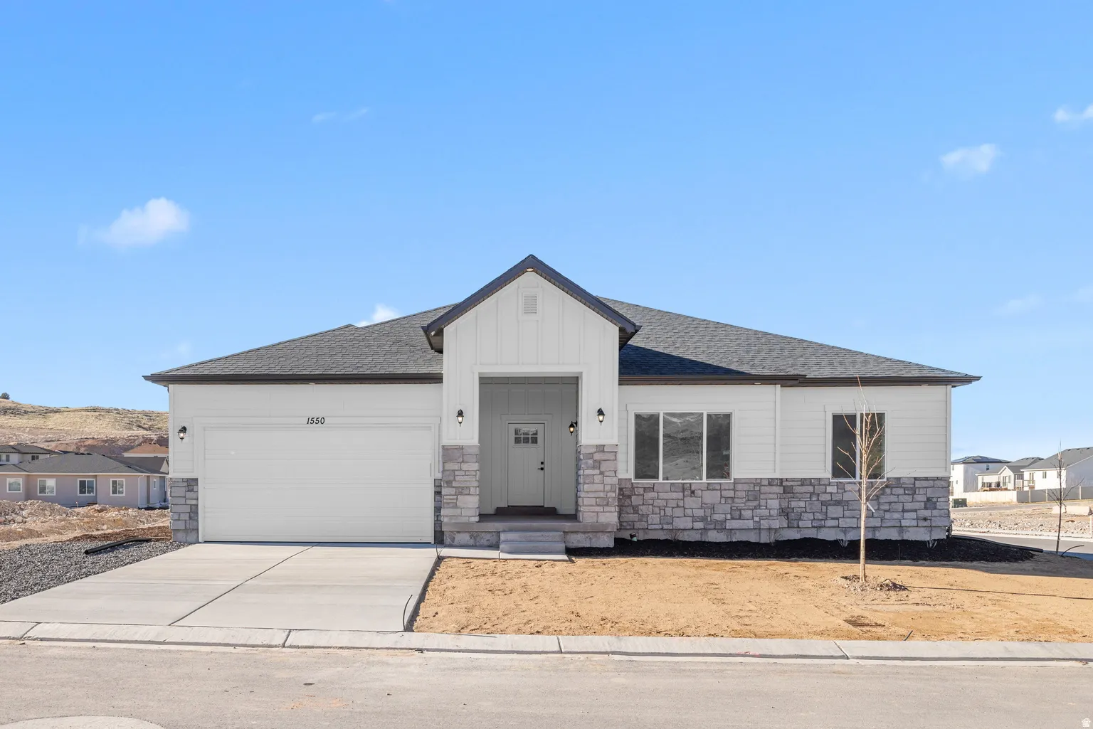 View of front of property with stone siding, a shingled roof, a garage, and concrete driveway