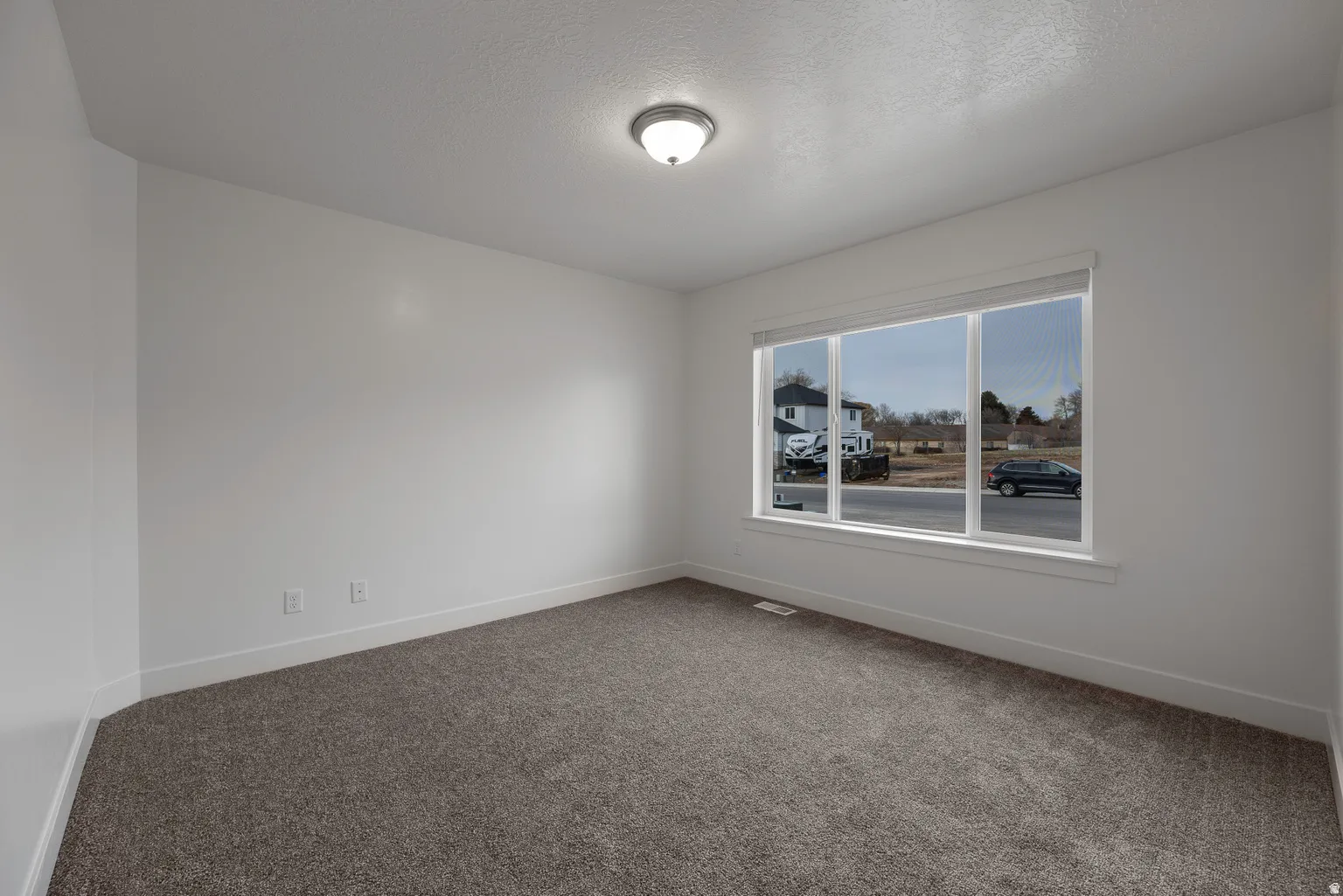Unfurnished room featuring dark colored carpet and a textured ceiling