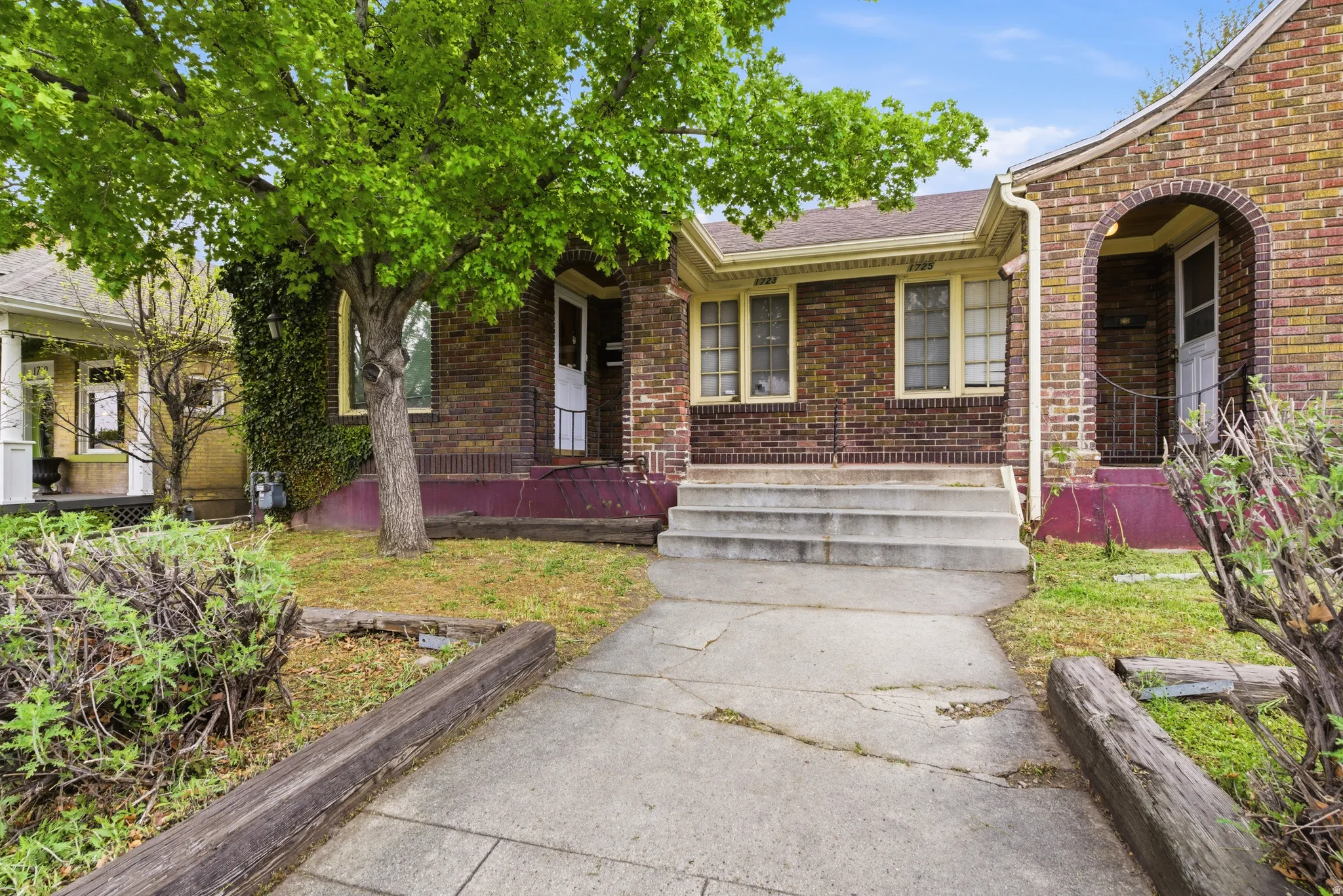 Doorway to property featuring brick siding and roof with shingles