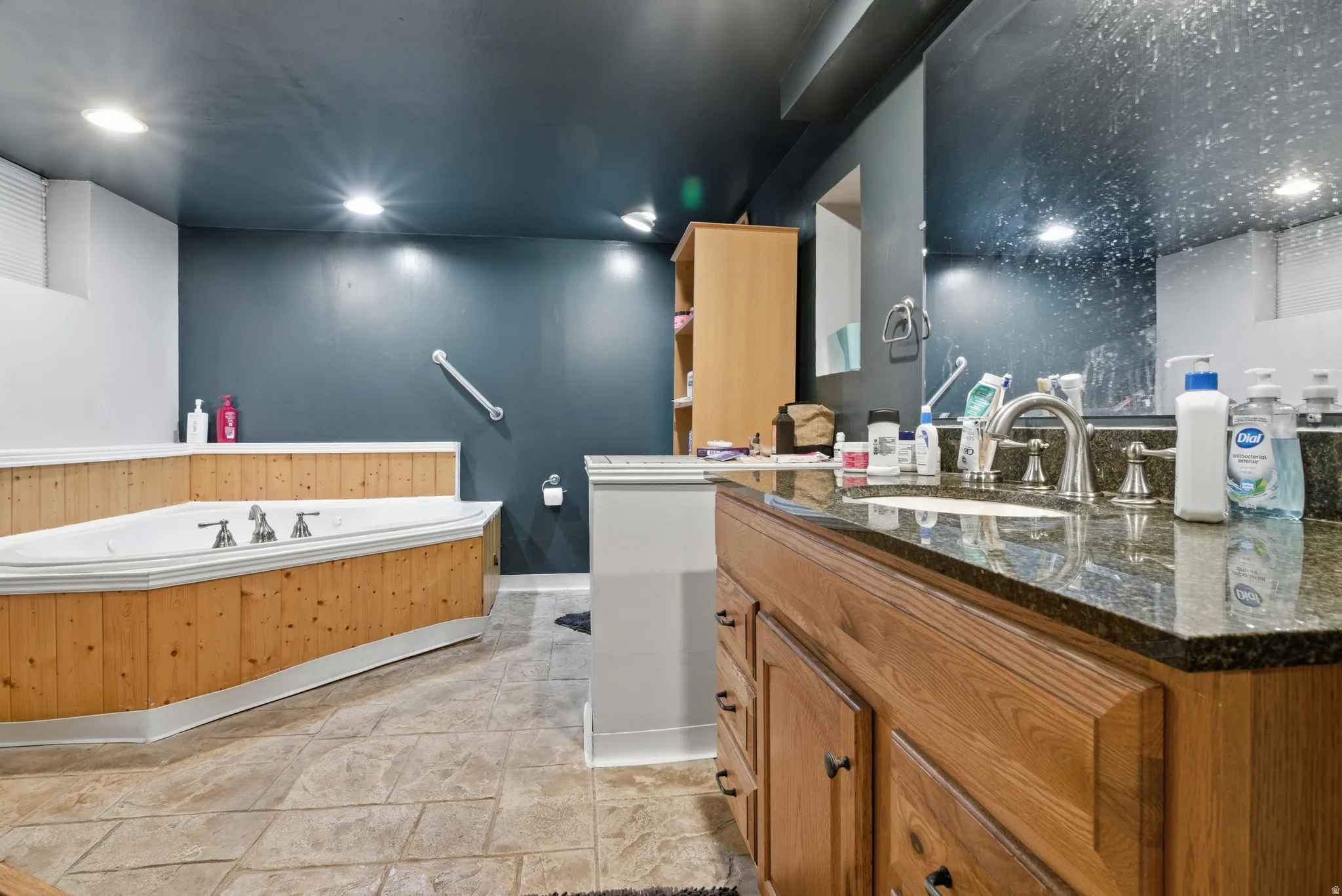 Full bath with vanity, a bath, recessed lighting, and light stone finish flooring