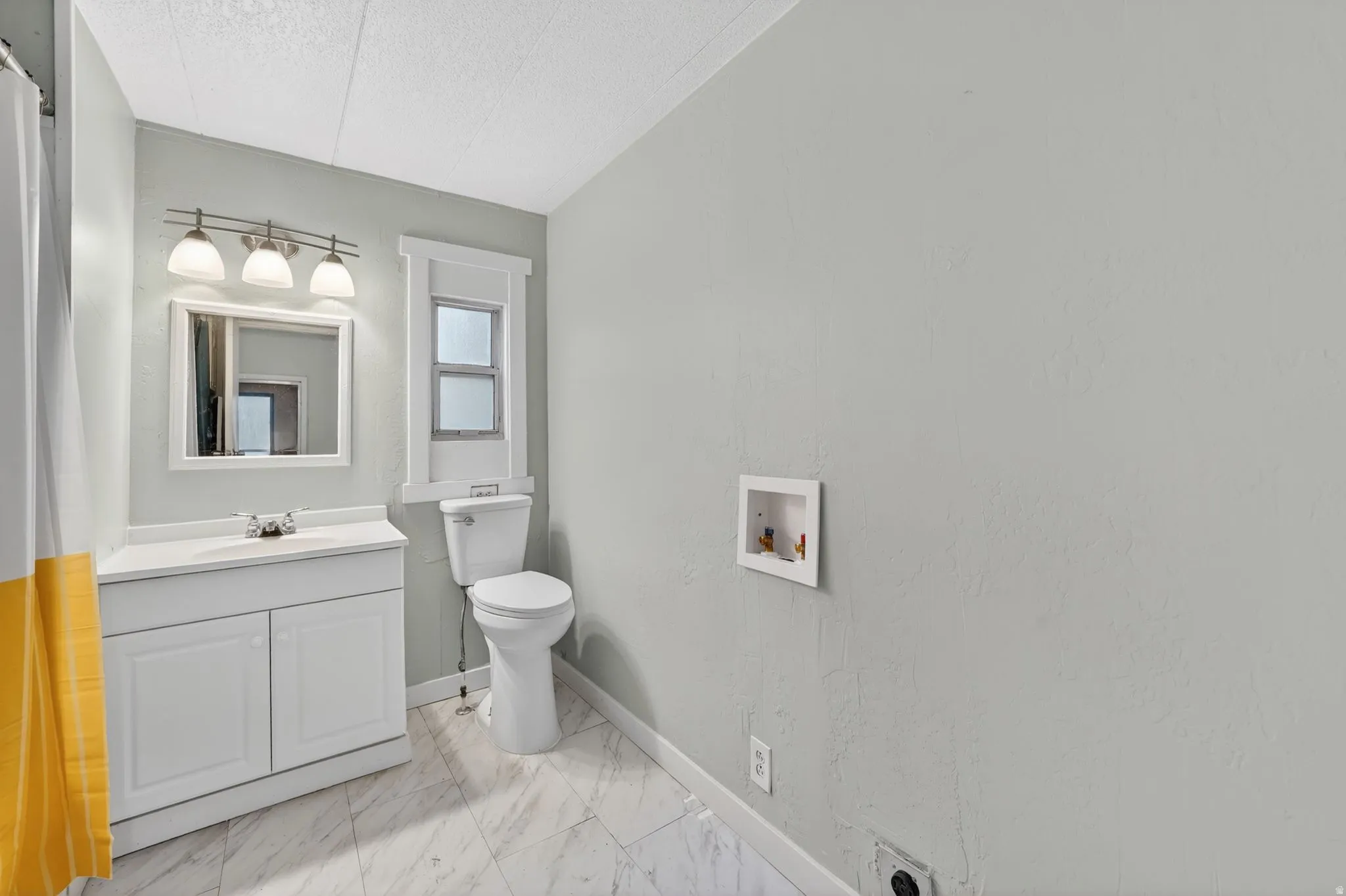 Bathroom featuring vanity, light marble finish flooring, a textured ceiling, and a shower with curtain