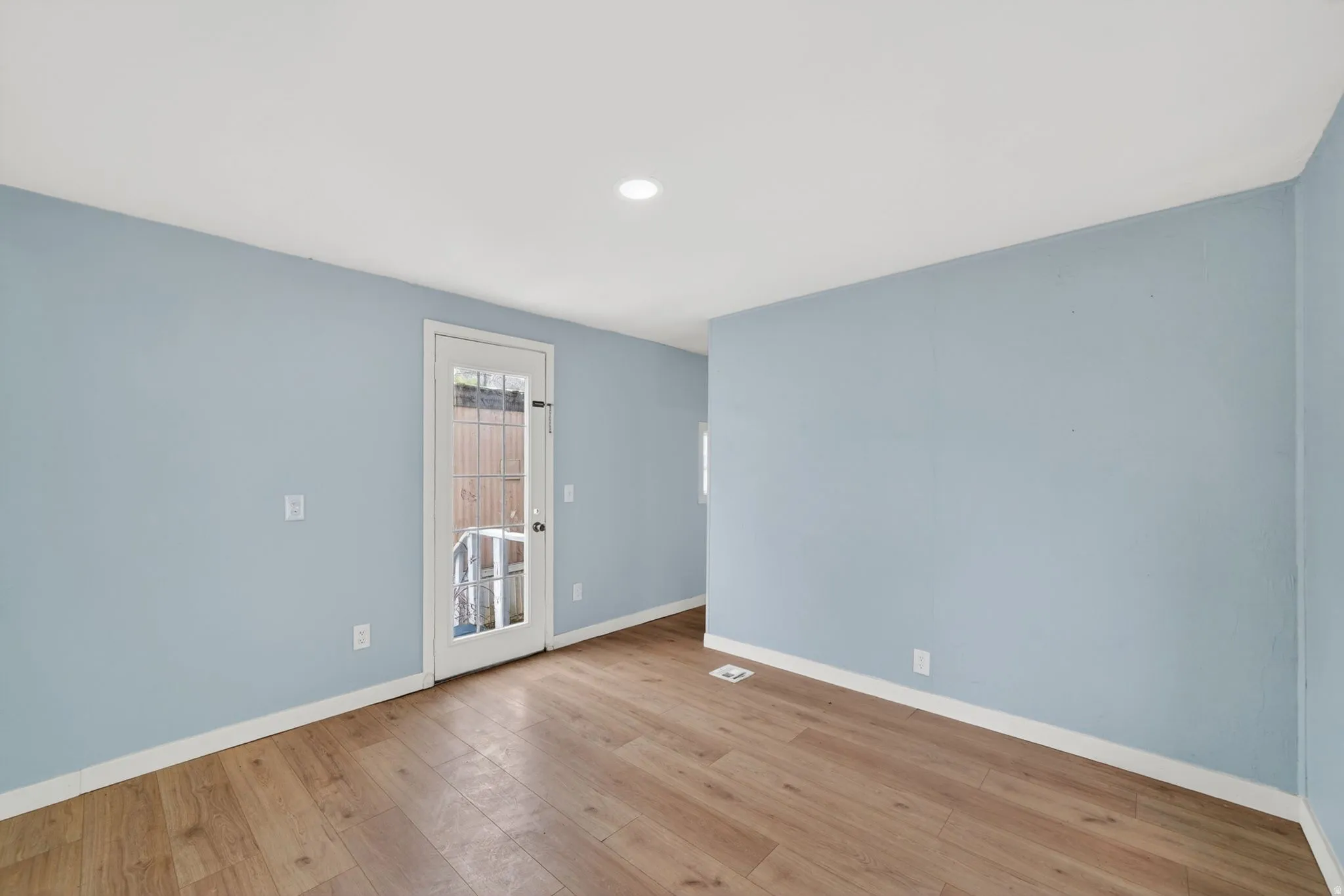 Empty room with light wood-style floors and recessed lighting