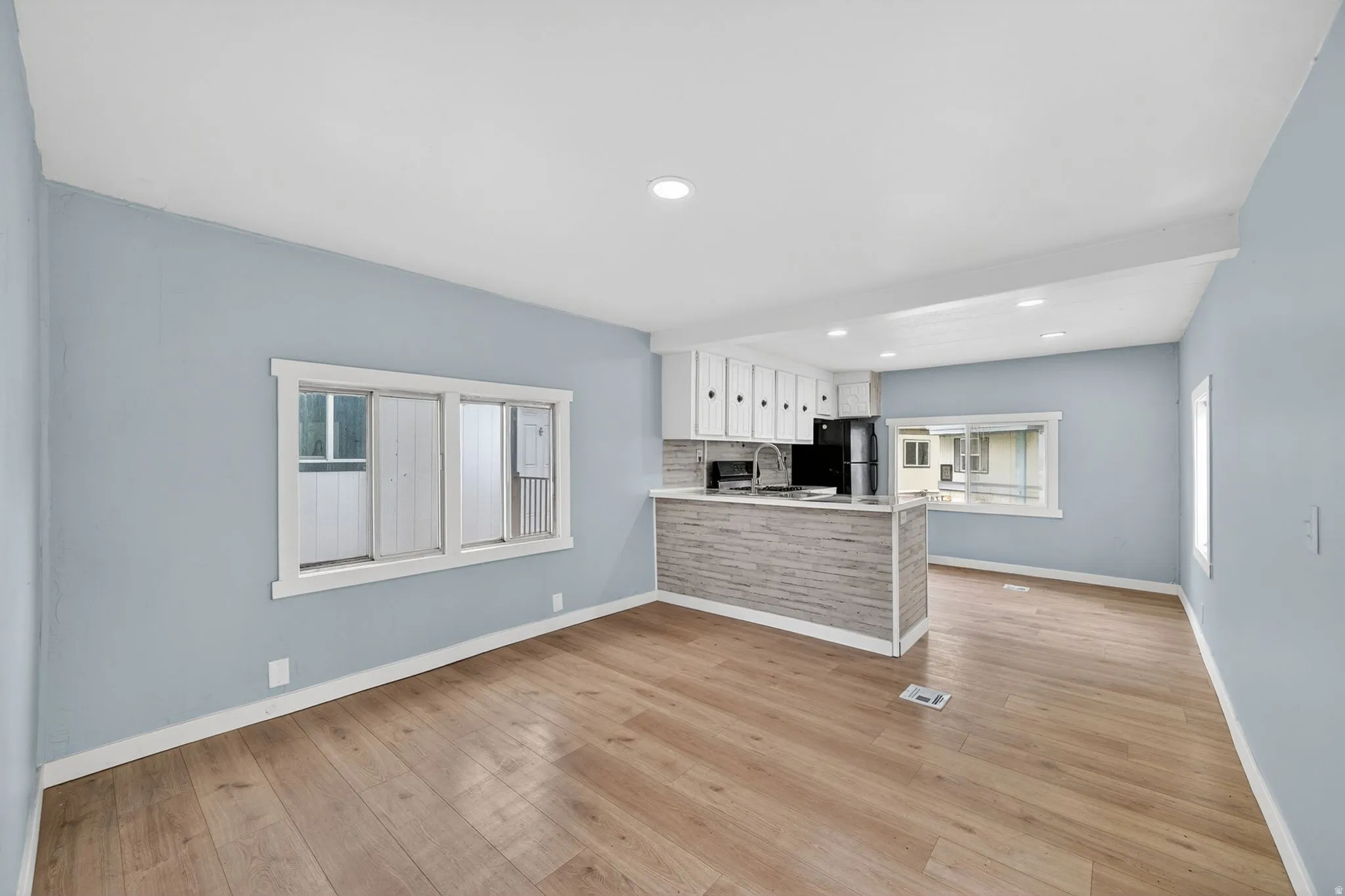 Unfurnished living room featuring recessed lighting, light wood finished floors, and healthy amount of natural light