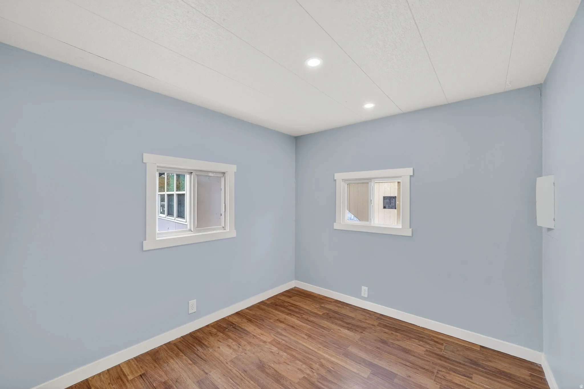 Empty room with wood finished floors, plenty of natural light, and recessed lighting
