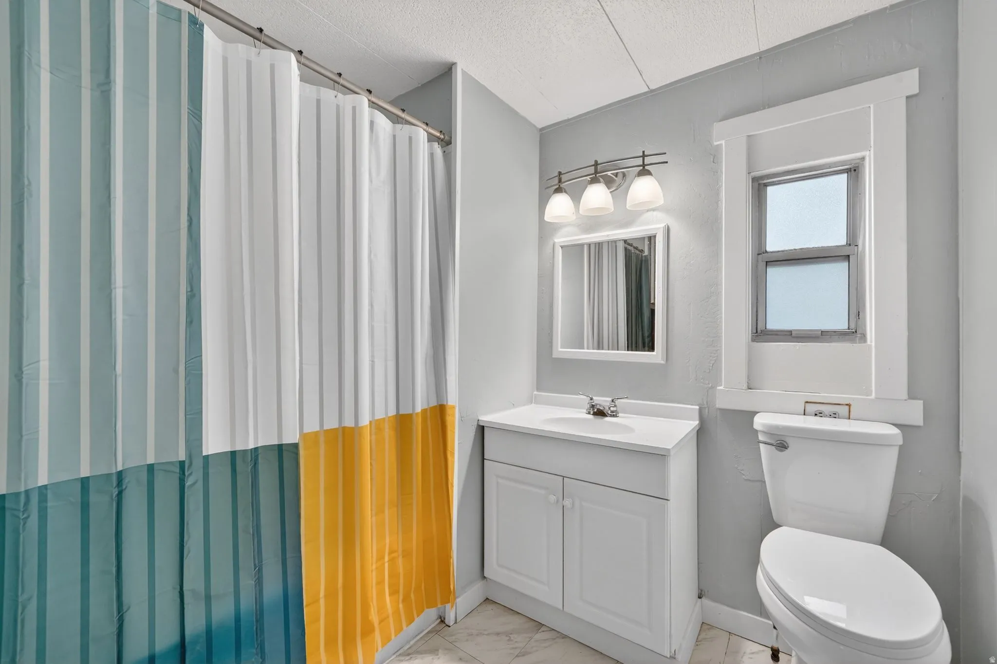 Full bathroom with vanity, a shower with curtain, a textured ceiling, and light marble finish flooring