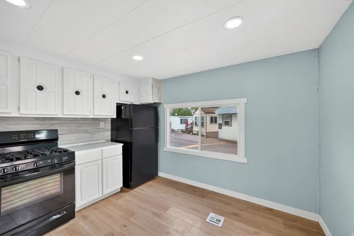 Kitchen featuring black appliances, white cabinetry, light wood finished floors, tasteful backsplash, and recessed lighting
