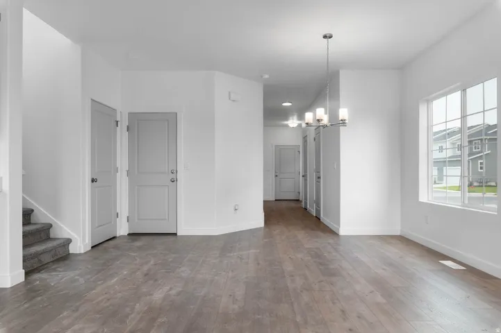 Open-concept living area featuring wood-finish flooring, white walls, and a multi-pane window