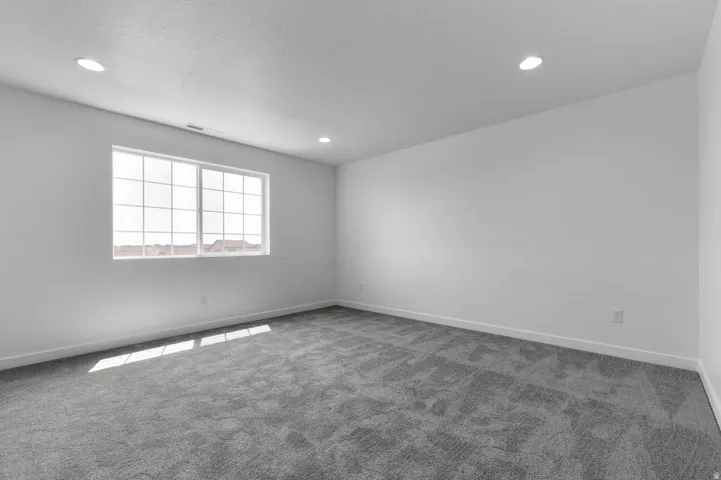 Neutral tone wall paint, recessed ceiling lighting, and gray patterned carpeting