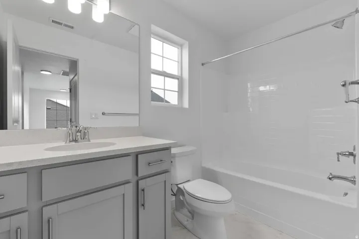 Contemporary bathroom featuring a vanity with gray cabinetry, a light-toned countertop, and an integrated sink