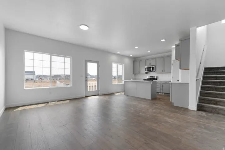Open-concept living area featuring wood-finish flooring, recessed lighting, and large windows