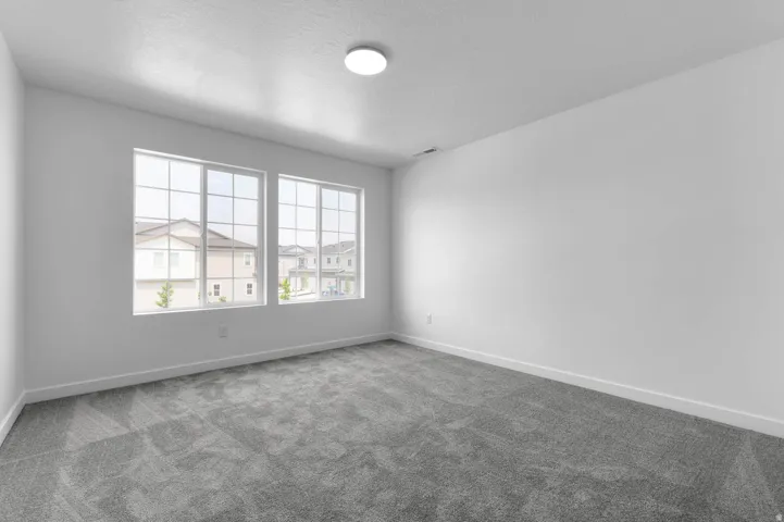 Spacious room featuring gray carpeting, white baseboards, and two multi-pane windows