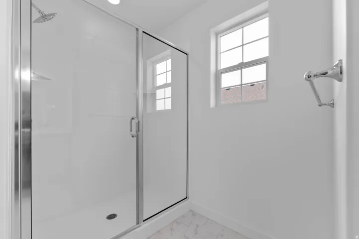Shower enclosure with glass sliding door and chrome hardware, featuring a rainfall showerhead