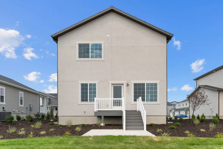 Rear exterior featuring a neutral stucco facade and a gray-decked porch with white railings